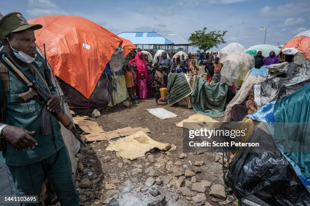 Security guard stands amid Somalis displaced by drought and war, who stand beside a makeshift hut at the Sebedow Camp as they set up in more than 500...