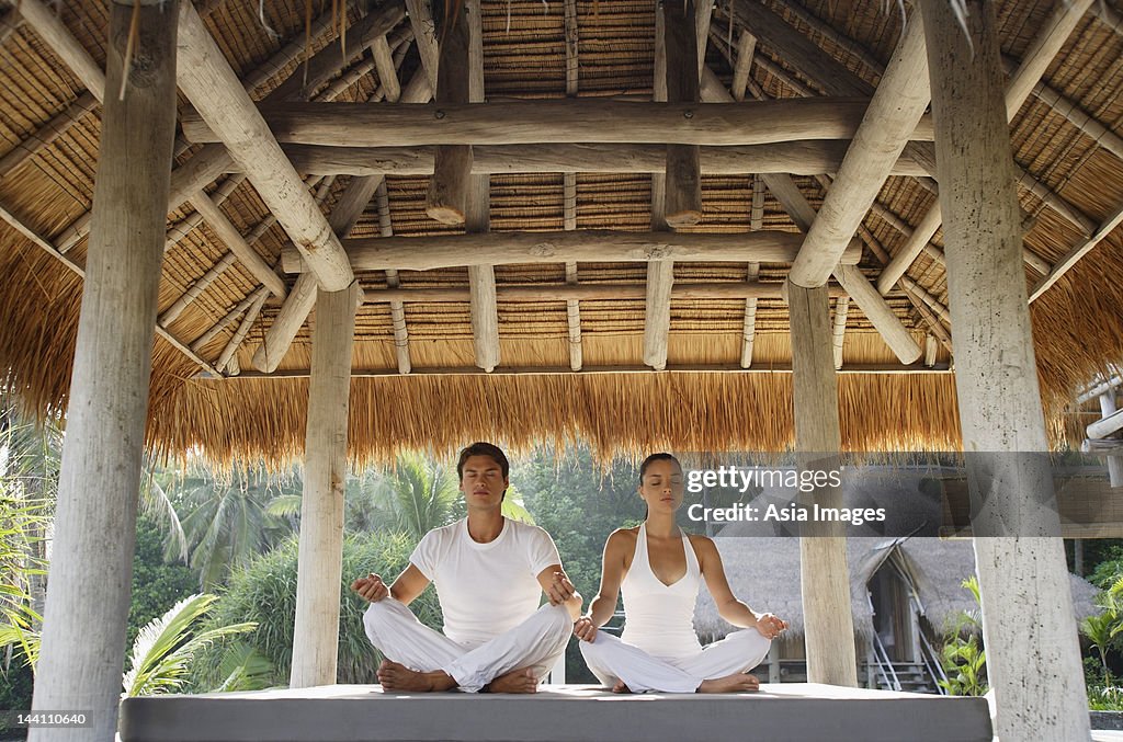 Young couple doing yoga in outdoor sala