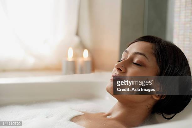 woman reclining in bathtub - body care and beauty stock pictures, royalty-free photos & images