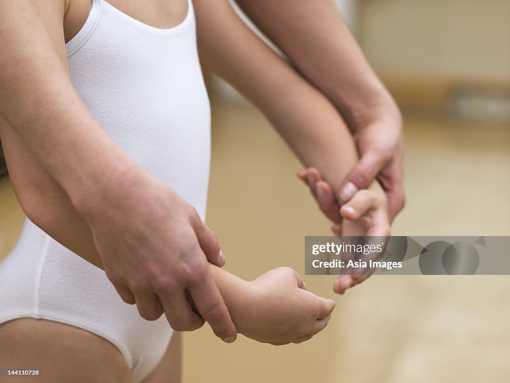 Young ballerina being helped by teacher