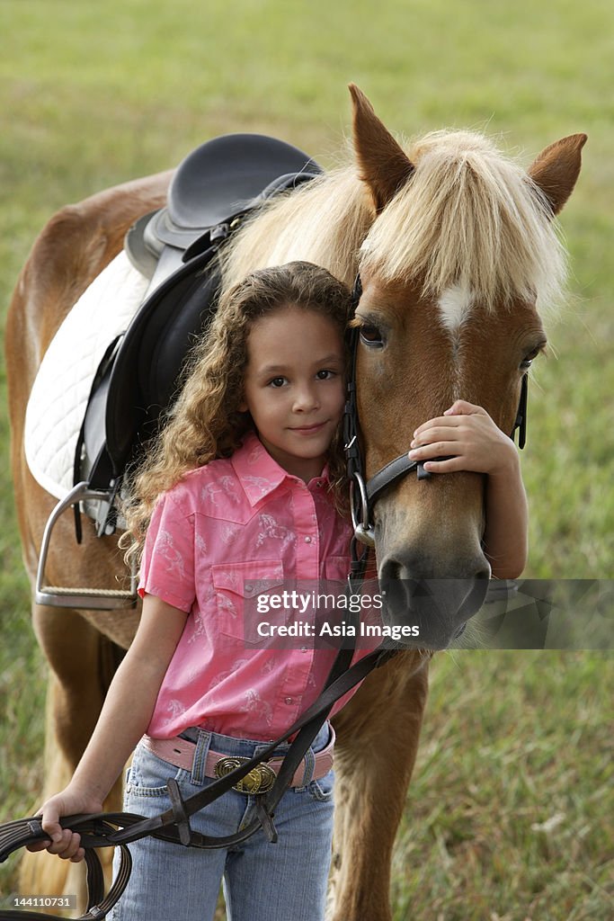 Young girl hugging nose of pony