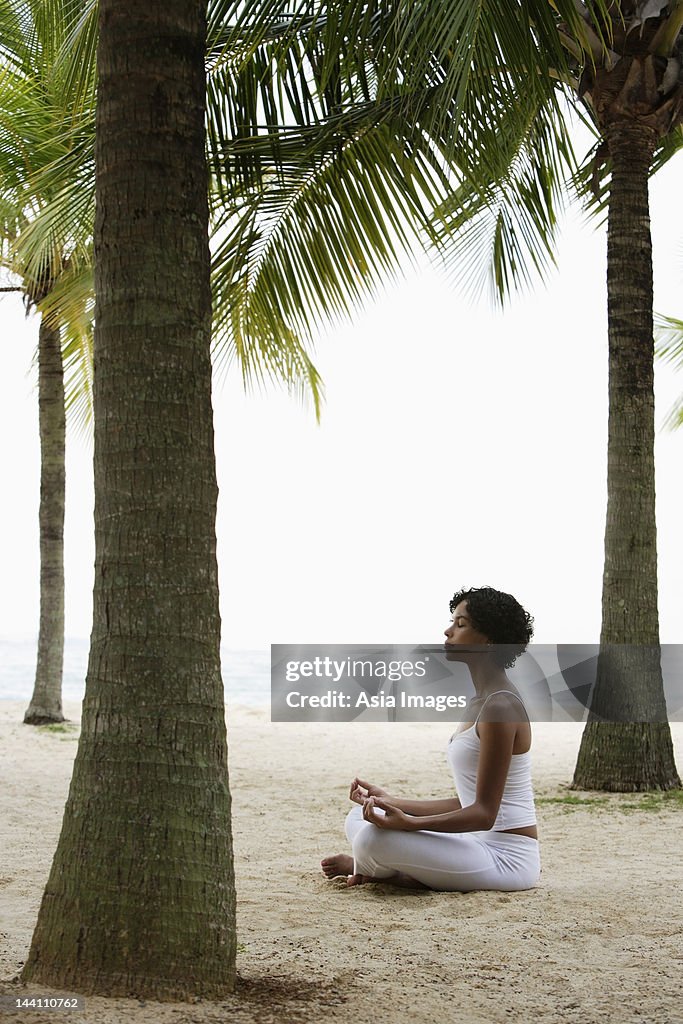 Junge Frau tun yoga am Strand unter Kokospalmen, Meditieren