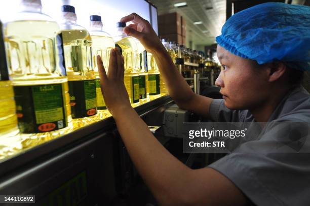 In this picture taken on May 9 a worker inspects the bottles of corn oil produced at a factory in Zouping, northeast China's Shandong province....