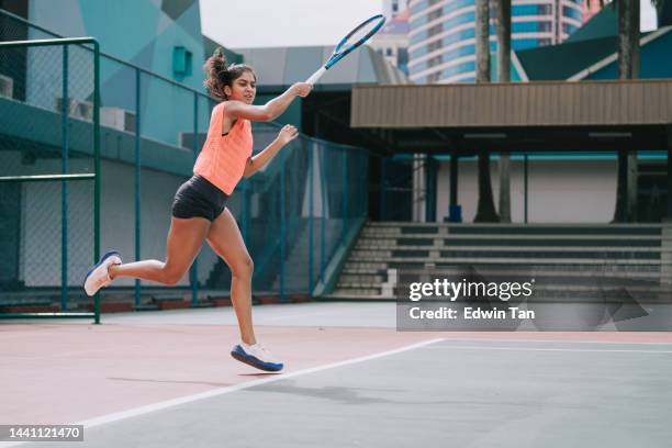 asiatische indische tennisspielerin beim training auf dem tennisplatz am wochenendmorgen - bildtechnik stock-fotos und bilder