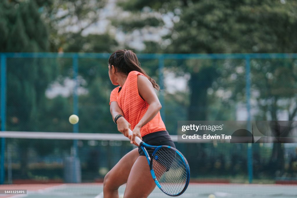 Asian Indian female Tennis Player Serving The Ball practicing at tennis court with coach guidance