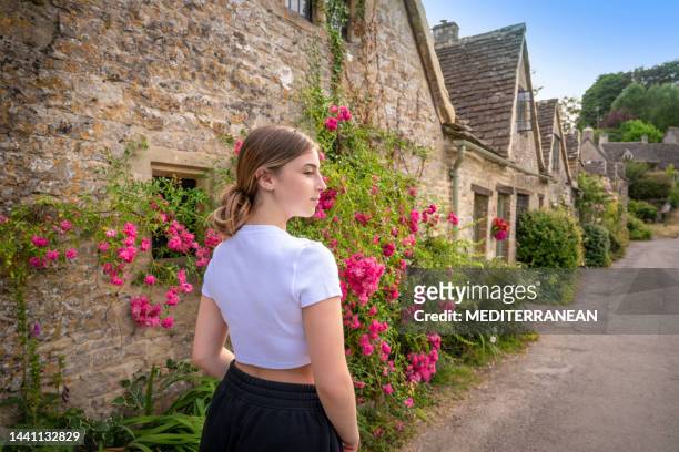 bibury, young girl blond tourist student in arlington row in the england cotswolds uk - stone house stock pictures, royalty-free photos & images
