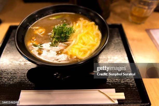 a bowl of japanese curry udon with egg on tray with chopsticks - カレーうどん ストックフォトと画像