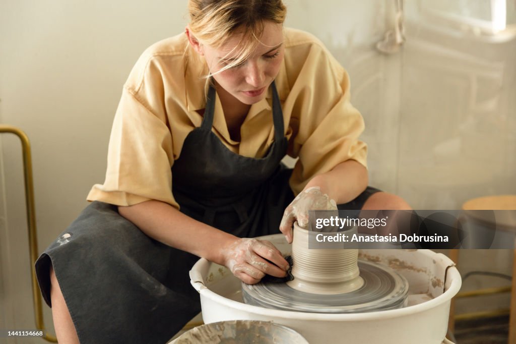 Female potter making ceramic vase on potter's wheel