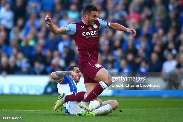 John McGinn of Aston Villa is tackled by Lewis Dunk of Brighton & Hove Albion during the Premier League match between Brighton & Hove Albion and...