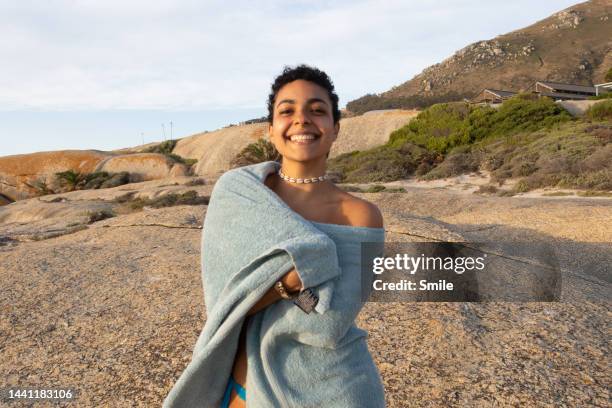 portrait of young woman wrapped in blue banket smiling at camera - banket stock-fotos und bilder