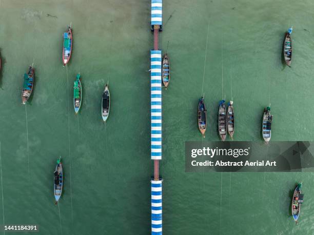 drone image looking down on moored fishing boats and a pier, patong beach, phuket, thailand - tourism industry stock pictures, royalty-free photos & images