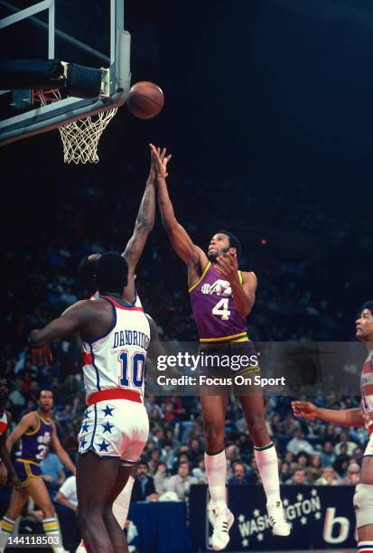 Adrian Dantley of the Utah Jazz shoots over Elvin Hayes and Bob Dandridge of the Washington Bullets during an NBA basketball game circa 1981 at the...