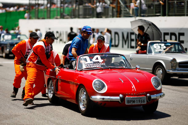 Track marshals help Fernando Alonso of Spain and Alpine F1 as his car stops on the drivers parade prior to the F1 Grand Prix of Brazil at Autodromo...