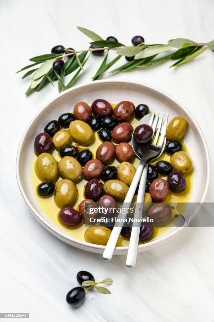 Green and black olives with olive oil and herbs