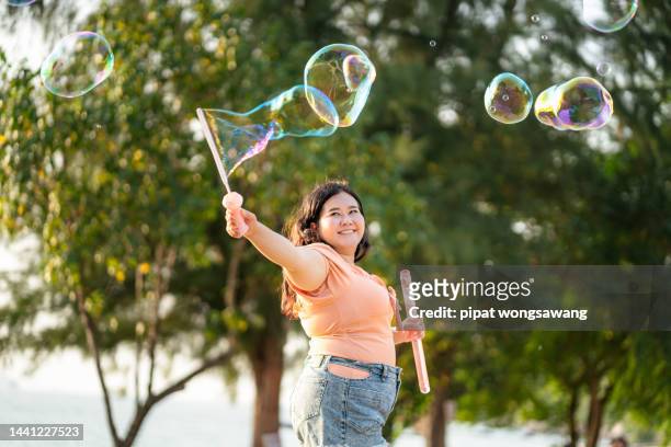 plus size ladies having fun playing bubbles in the evening atmosphere. - fat asian woman stock pictures, royalty-free photos & images