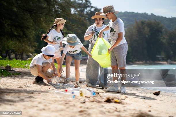 children's volunteers they are collecting plastic waste on the beach to help reduce marine pollution. - chubby asian girl stock-fotos und bilder