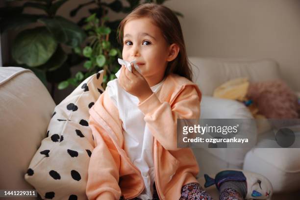 little girl gets cold and blows her nose at home. - covering nose stock pictures, royalty-free photos & images