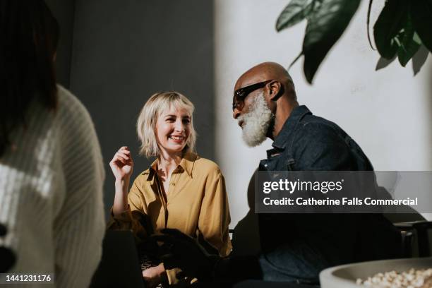 conceptual image of a man and a woman sitting side-by-side in a sunny, modern environment. - candid women fotografías e imágenes de stock