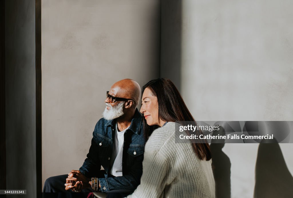 Conceptual, simple image of a man and a woman sitting beside each other.