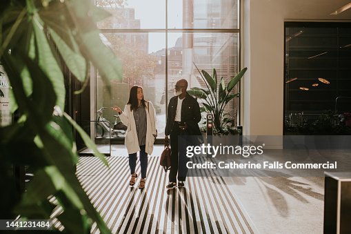 A woman and a man enter a modern building and look around with curiosity A woman and a man enter a modern building and look around with curiosity