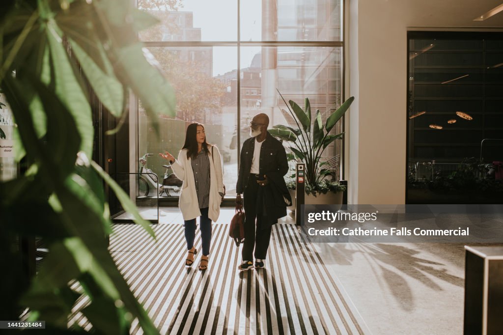 A woman and a man enter a modern building and look around with curiosity