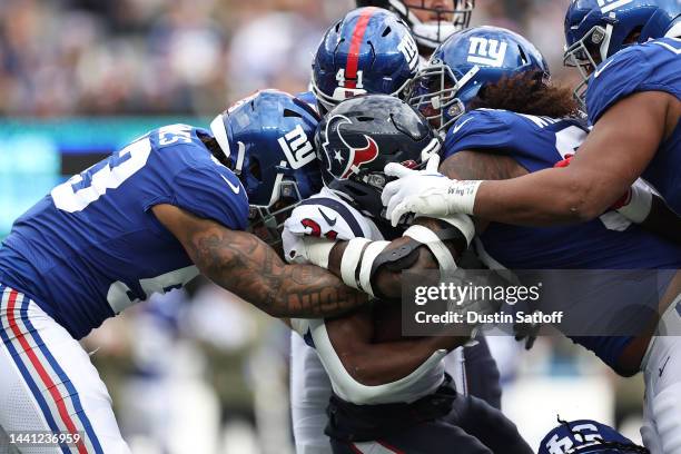 Dameon Pierce of the Houston Texans is tackled by Oshane Ximines of the New York Giants, Micah McFadden, and Leonard Williams of the New York Giants...