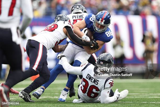 Tanner Hudson of the New York Giants is tackled by Jonathan Owens of the Houston Texans, Christian Kirksey, and Jalen Pitre of the Houston Texans...