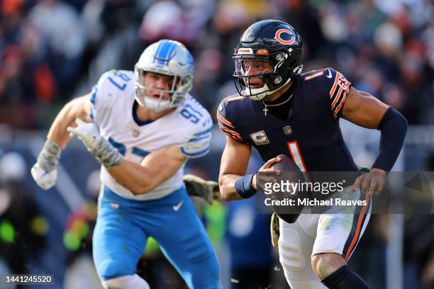 Justin Fields of the Chicago Bears scrambles while Aidan Hutchinson of the Detroit Lions pursues during the fourth quarter at Soldier Field on...