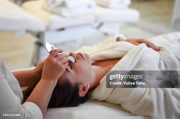 woman having an gua sha facial massage - beauty treatment stock pictures, royalty-free photos & images