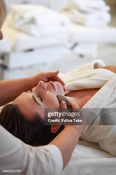 massage facial skin with gua sha scrapper. - facial massage stock pictures, royalty-free photos & images