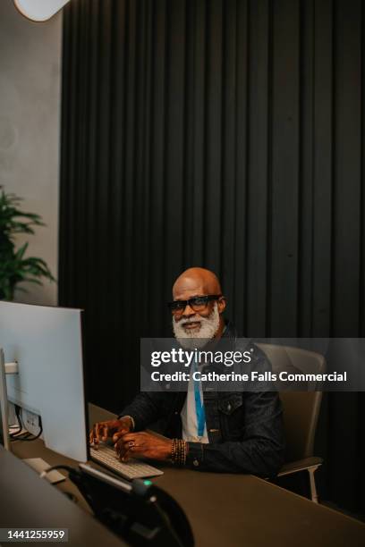 a friendly male receptionist sits at a desk and looks directly at the camera - bell telephone company stock pictures, royalty-free photos & images