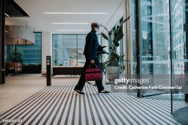 a man walks towards a revolving door in an office building - afterwork stock pictures, royalty-free photos & images