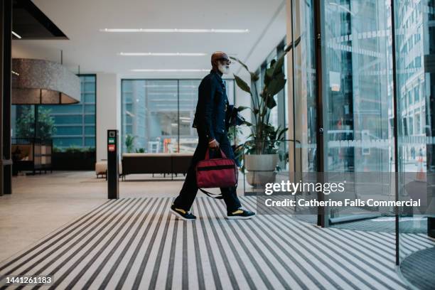 a man walks towards a revolving door in an office building - leaving city stock pictures, royalty-free photos & images