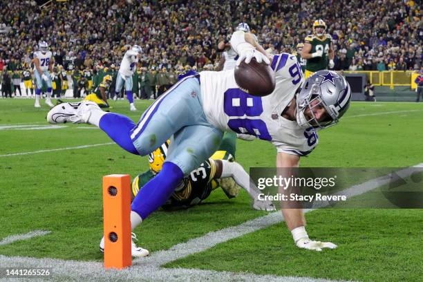 Dalton Schultz of the Dallas Cowboys dives past Adrian Amos of the Green Bay Packers while scoring a touchdown during the second quarter at Lambeau...