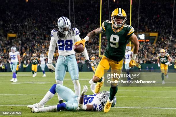 Christian Watson of the Green Bay Packers breaks a tackle from DaRon Bland of the Dallas Cowboys and Malik Hooker of the Dallas Cowboys while scoring...