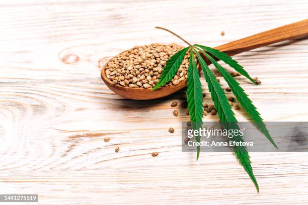 cannabis leaf and hemp seeds in spoon on wooden background. concept of using healthy food supplements - macrobiotic diet stock pictures, royalty-free photos & images