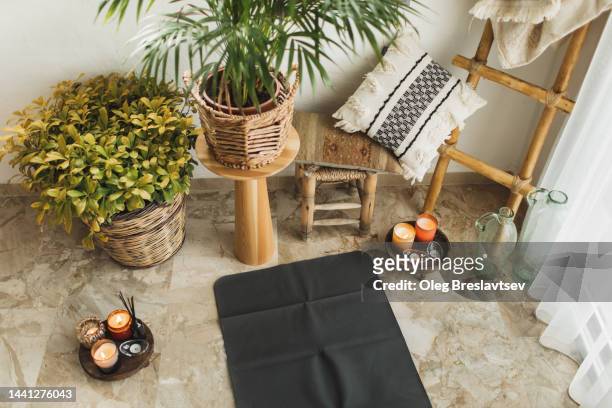 cozy place for yoga practice at home. yoga mat, candles with aroma sticks, house plants - yoga kissen stock-fotos und bilder