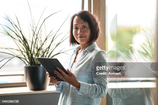 portrait of a beautiful mature asian businesswoman with a digital tablet - lawyers serious stock pictures, royalty-free photos & images
