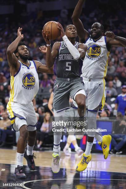 De'Aaron Fox of the Sacramento Kings drives to the basket against Andrew Wiggins and Draymond Green of the Golden State Warriors in the second...