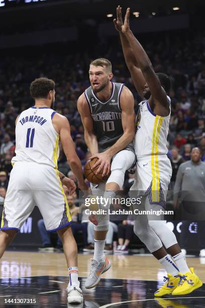 Domantas Sabonis of the Sacramento Kings is guarded by Klay Thompson and Draymond Green of the Golden State Warriors in the second quarter at Golden...