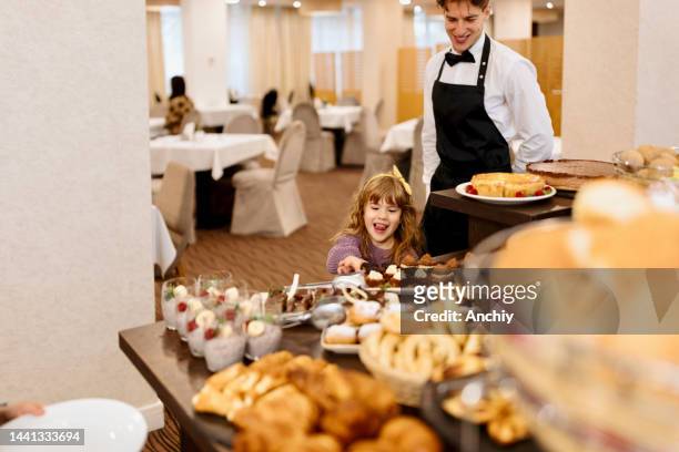 little girl looking at cakes on a buffet table - buffet stockfoto's en -beelden