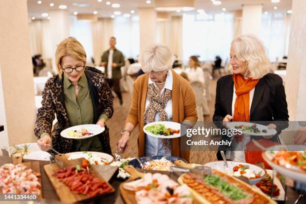 amigos mayores disfrutando del desayuno buffet en el hotel o restaurante - buffet fotografías e imágenes de stock