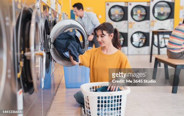 woman using a washing machine at the laundromat. - money laundery stockfoto's en -beelden