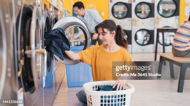 woman using a washing machine at the laundromat. - money laundery stock pictures, royalty-free photos & images