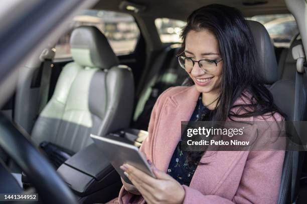 brunette woman browsing on a tablet - car mobile stockfoto's en -beelden