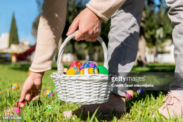 woman laying down easter eggs from a basket - paaseieren stockfoto's en -beelden