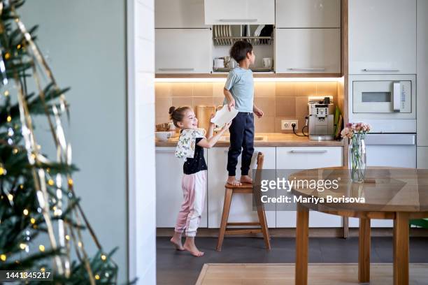 the sister helps her brother to put clean dishes in place. - cleaning up after party stock-fotos und bilder