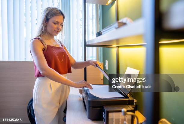 woman at her office printing some papers - photocopier stockfoto's en -beelden