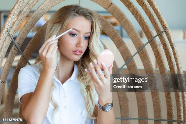 portrait of beautiful young woman putting make-up on, using eyebrow pencil - eyebrow pencil stock pictures, royalty-free photos & images