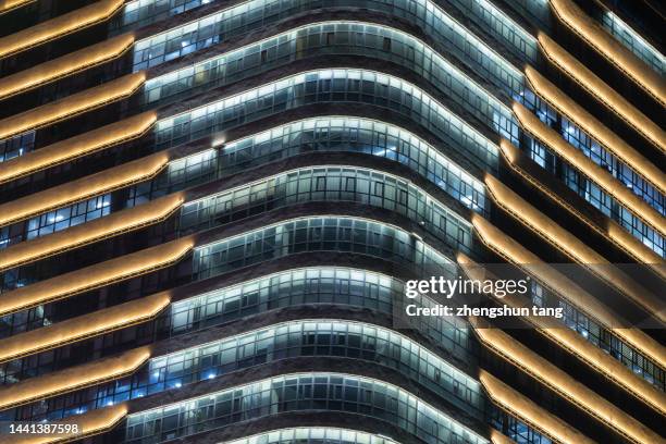 dalian, china. gold colored glass curtain wall of office building at night. - curtain wall facade stock pictures, royalty-free photos & images